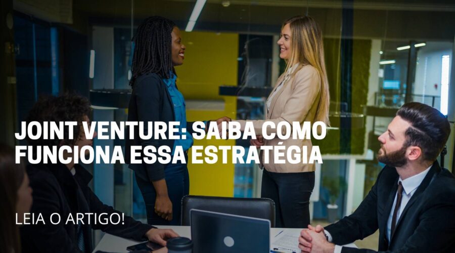 A imagem deste artigo reflete 5 pessoas, sendo três sentada e duas em pé dentro de uma sala. As pessoas em pé estão apertando a mão parecendo que está fechando uma negociação e no meio da imagem está escrito o título do artigo: Joint Venture saiba como funciona essa estratégia